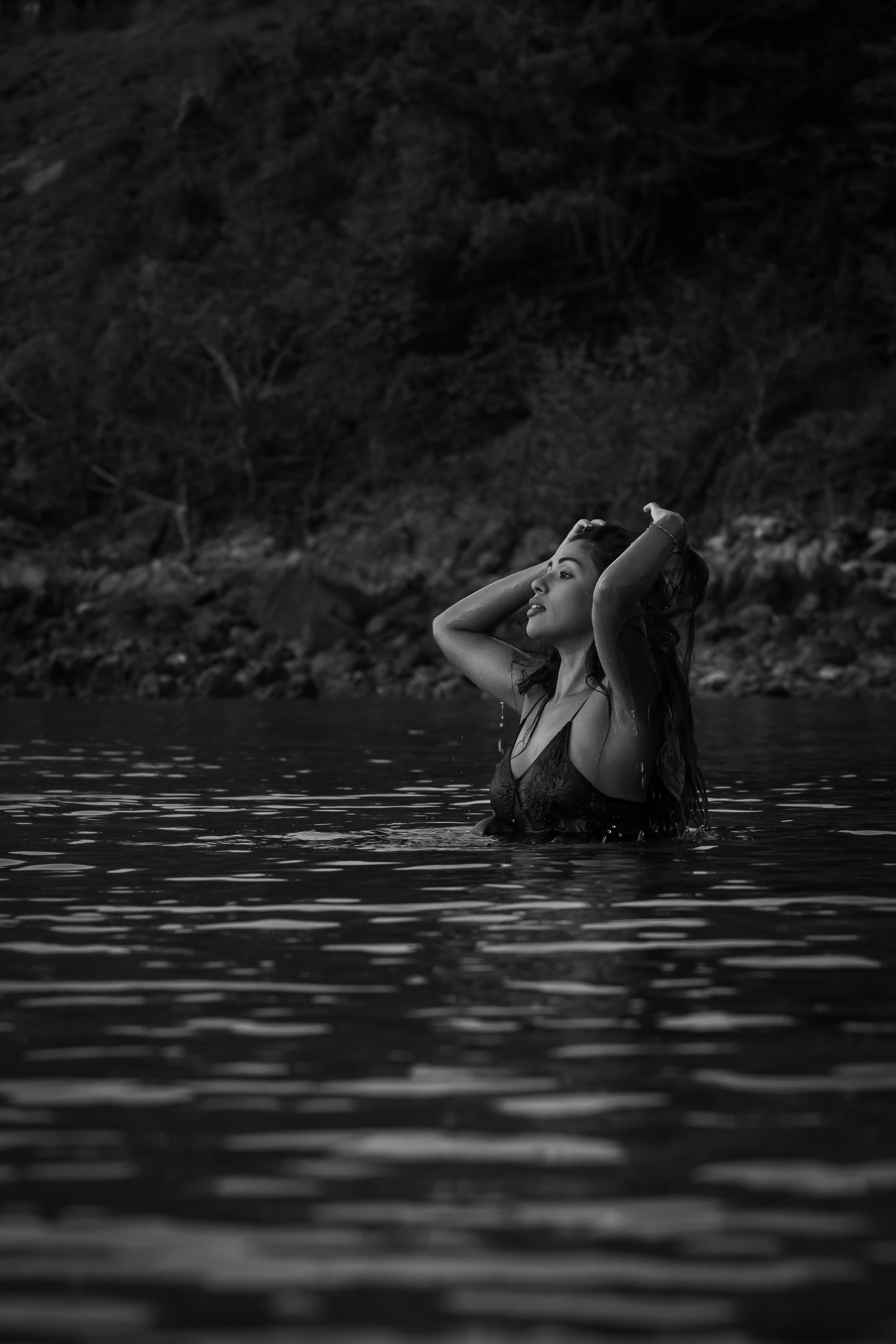 Schwarz-Weiß-Aufnahme einer Frau im Wasser, die sich mit den Händen durch ihr Haar fährt.